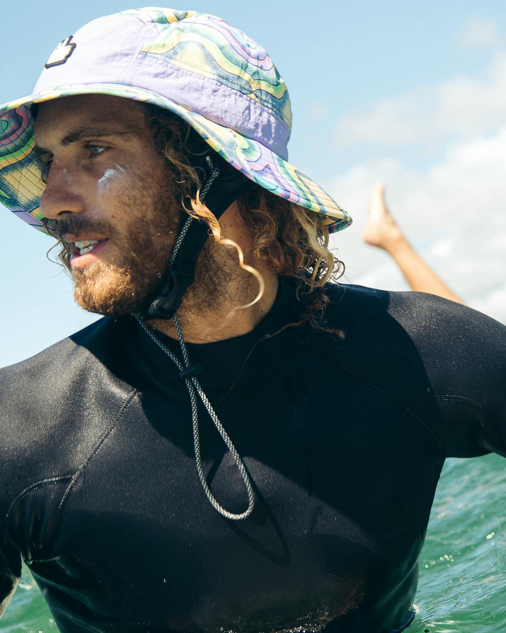 Person wearing a wetsuit and colorful hat in the ocean